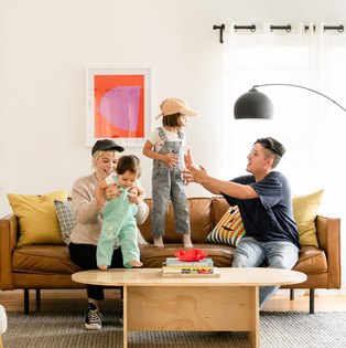 Two women playing with their kids in their living room