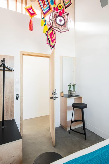 Native American art pieces hang from ceiling of a bedroom featuring high ceilings and concrete floor.