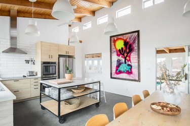 The kitchen with white walls, beamed ceilings and colorful wang hanging.