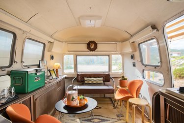 Inside the Airstream trailer seating area with mid-century chairs and vintage cooler.