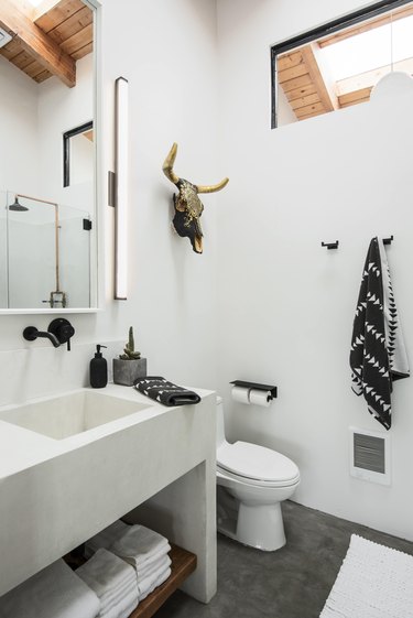 A white concrete bathroom with sink and toilet.