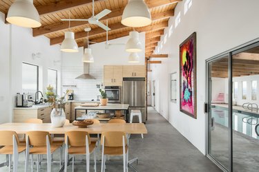 The kitchen and dining area with wood beamed ceiling and slider door to indoor pool.