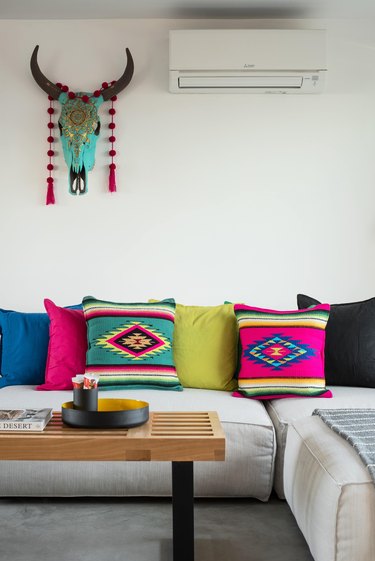 Color textiles pillows, a painted cattle skull and sectional couch.