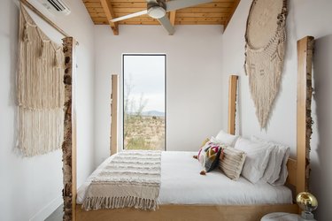 A bedroom with view featuring wall hangings and wood beamed ceilings.