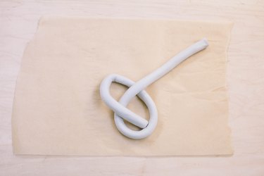 Shaping tube of air dry clay into a knot