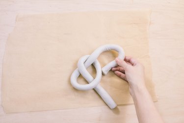 Shaping tube of air dry clay into a knot