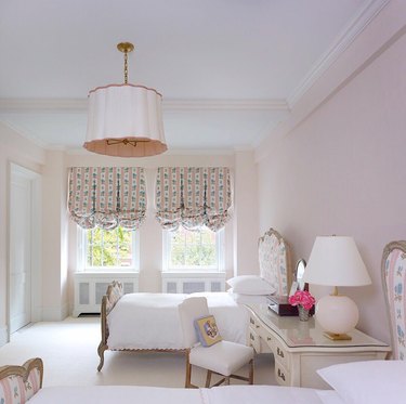 Victorian pink bedroom with feminine furnishings and upholstered headboard