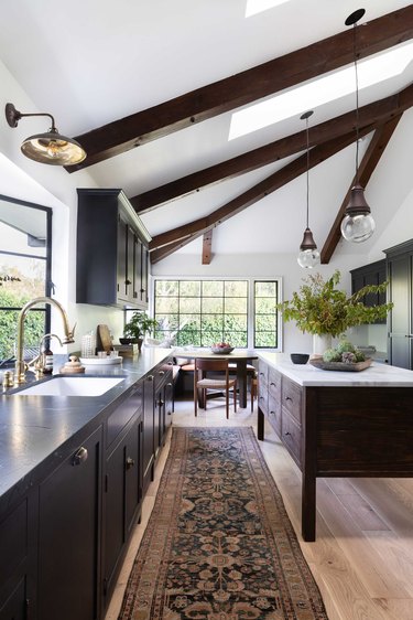 kitchen with exposed beams, black cabinets and wood island