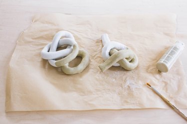 two clay knot sculptures painted halfway with tan paint