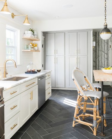 Gray tile herringbone kitchen floor in white, airy kitchen and brass details