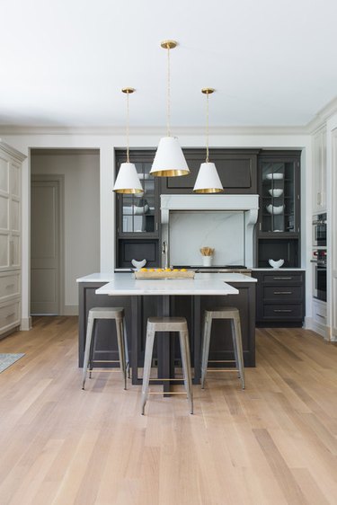 Navy blue T-shaped kitchen island with three gold and white pendant lights