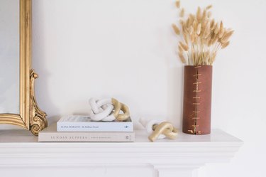 two diy clay knot sculptures on mantel with mirror, books and dried flowers