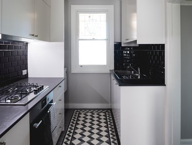 Black and white inlay tile, black tile backsplash, white cabinets.