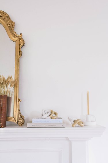 two diy clay knot sculptures on mantel with gold mirror, books and candle