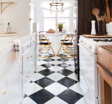 Black and white checkered floors, white cabinets and stove in vintage inspired kitchen with breakfast area.