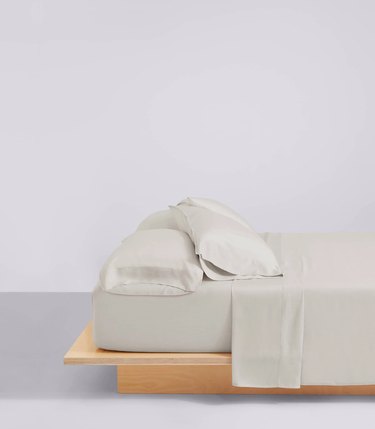 bed with wood frame and gray bedsheets