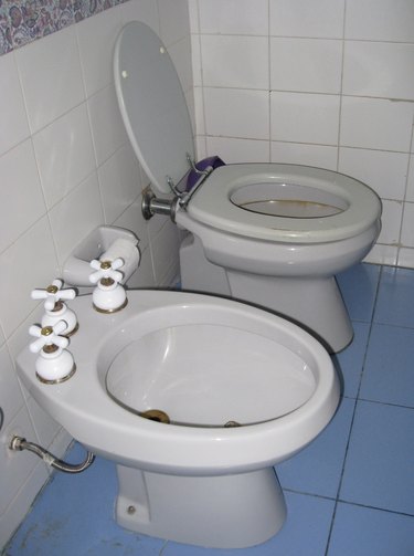 white toilet next to a white bidet in bathroom with blue and white tile