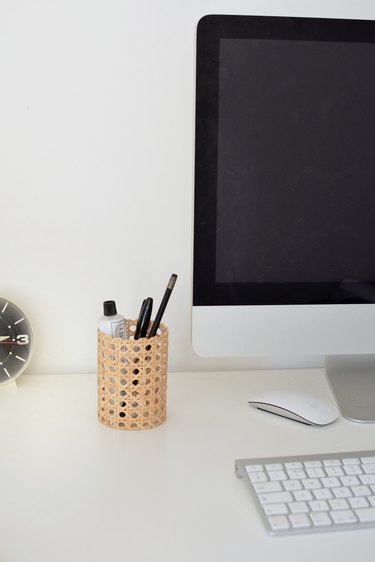 Cane pensil pot next to computer and keyboard.