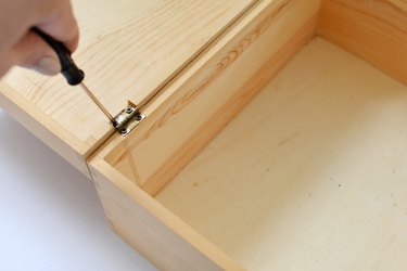 Open wooden box with screwdriver removing hinges.