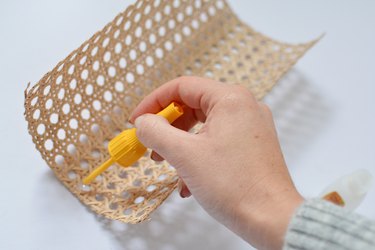 Hand applying glue to cane with yellow superglue brush