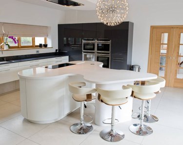 Oval kitchen island with curved dining area connected. All white cabinets and countertop.