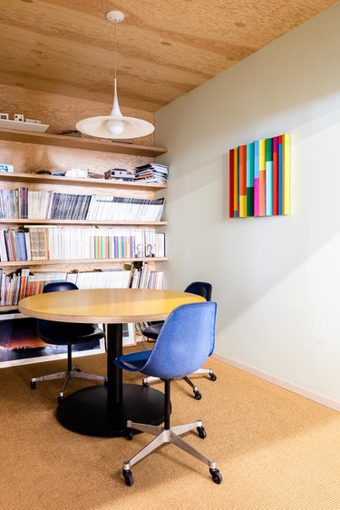 Office space with round wood table and blue chairs.