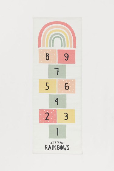 rug with hopscotch design in various colors and rainbow at the top, text at the bottom reads let's counts rainbows