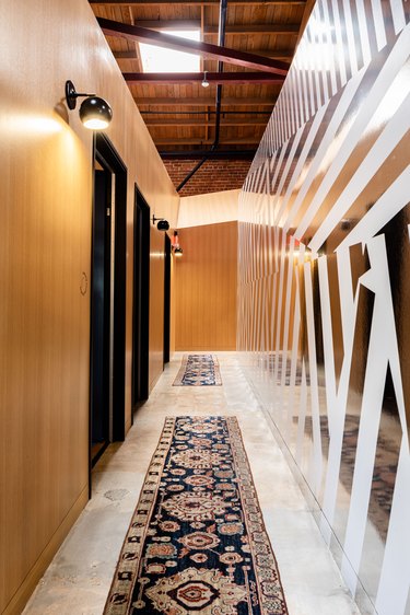 Long hallway with wood and wallpapered walls and Persian style runner