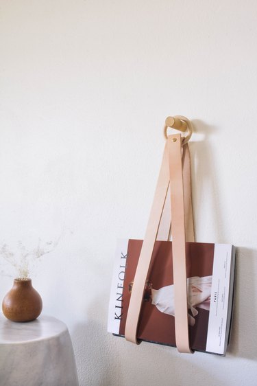 diy leather & wood magazine holder hanging on wall next to wood vase