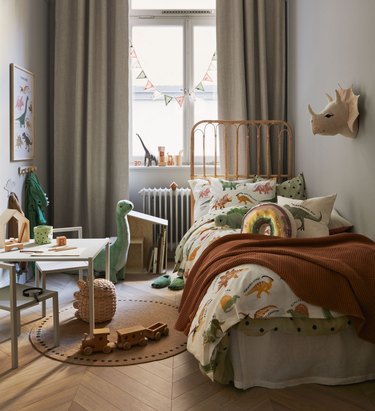 kids room with dinosaur-themed items and neutral-colored curtains
