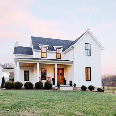 farmhouse style house with white rails and dark roof