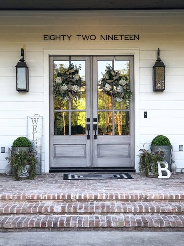 farmhouse style exterior with brick steps and gray glass doors