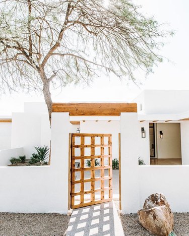 Desert style home with white exterior and reclaimed wood gate