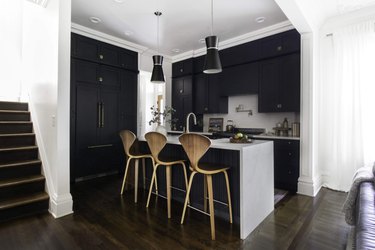 Dark wood kitchen flooring idea with modern bar stools and black cabinets
