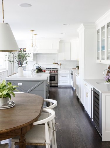 Dark wood kitchen flooring idea with white cabinets and white walls