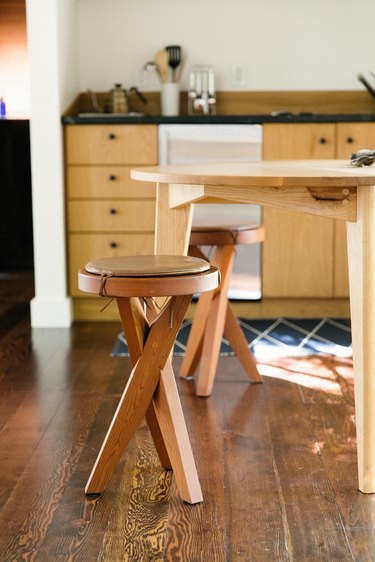 Dark wood kitchen flooring idea with wood stools, table, and cabinets