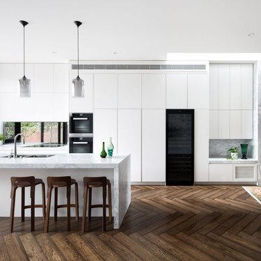 Dark wood kitchen flooring idea in a herringbone pattern and white cabinets