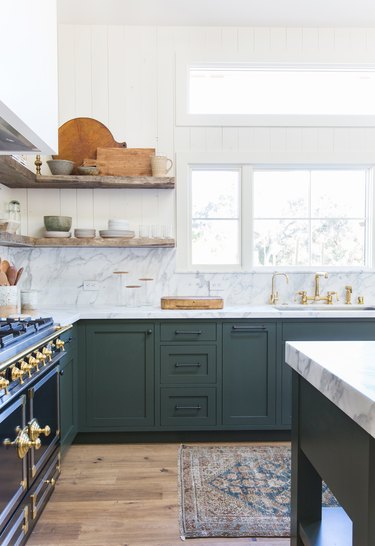 green kitchen cabinets with marble countertop and backsplash