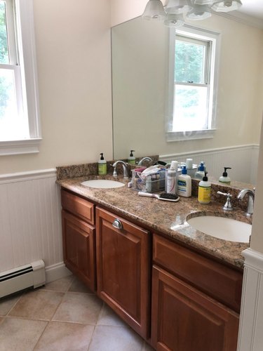 Painted bathroom cabinets before and after featuring dark wood cabinets and large mirror