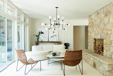 neutral living room with rock fireplace and modern chandelier