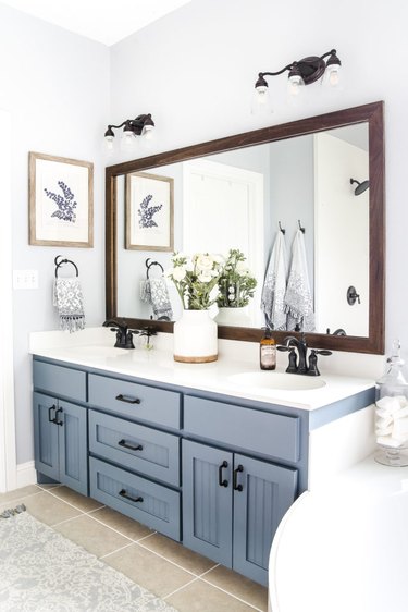 grayish blue bathroom vanity with large timber mirror and farmhouse lighting