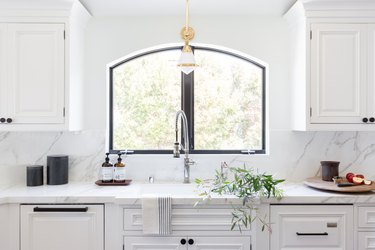 An all-white kitchen with marble counters and backsplash