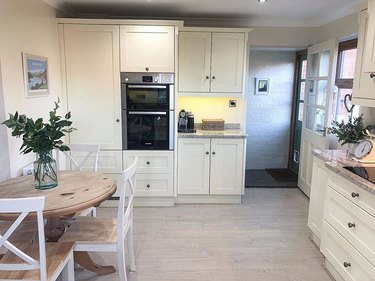 kitchen with white cabinets and light hardwood floor with dining table nearby