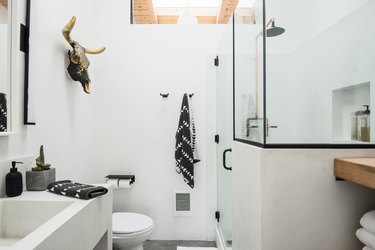 Desert-style white bathroom with skull on wall and black and white towels