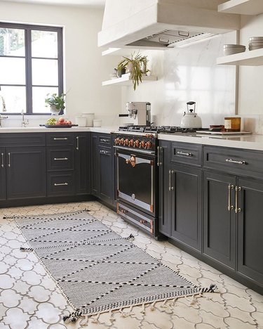 kitchen space with dark cabinets, patterned rug, and cream colored floor