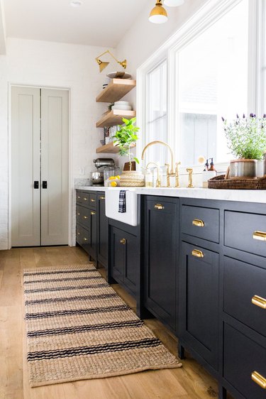 striped jute rug for kitchen floor with navy cabinets and brass fixtures