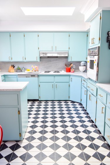 kitchen space with light blue cabinets and black and white patterned flooring