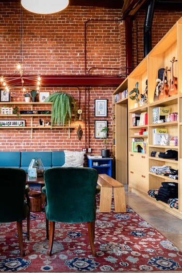 Office space interior with brick wall and blue chairs and couch.