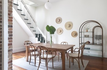 Dining room with wood table and hanging straw hats on wall