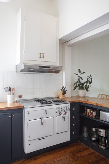 Antique white stove/oven in kitchen with blue cabinets